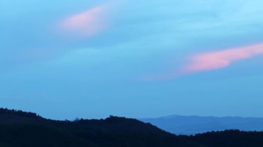 Sihirli mavi ve turuncu bulutlar gün batımında dağın üzerinde döner. Zaman ayarlı, rahatlama havası dramatik güzellik arka planı