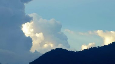 Gün batımında dağın tepesinde kabaran kümülüs bulutları kıvrılır. Zaman aşımı, gevşeme, dramatik hava güzelliği atmosfer gevşemesi, arka plan yuvarlanan kümülüs bulutları.