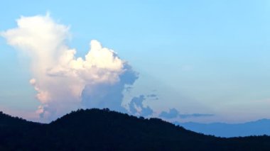 Bulutlar, gökyüzü konsepti, dağda dönen beyaz kabarık bulutlar, altın saatinde gün batımında mavi gökyüzü arkaplanı
