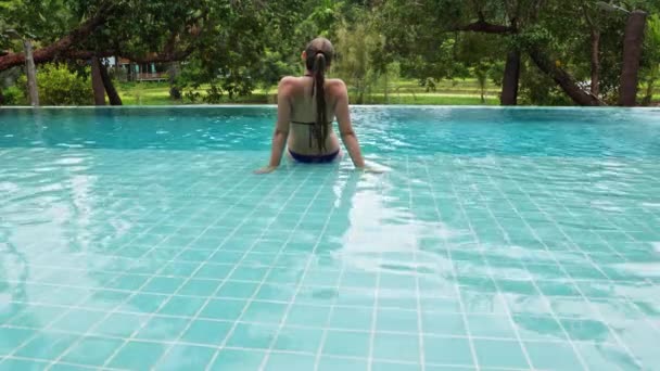 Woman Sits Edge Pool Swims Backdrop Tropical Vegetation Hotel Villa — Stock video