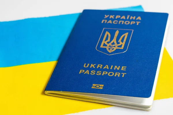 Ukrayna bayrağının arka planında Ukrayna biyometrik pasaportu. Yurt dışına seyahat için belge, konsept. Beyaz bir arkaplanda izole edilmiş