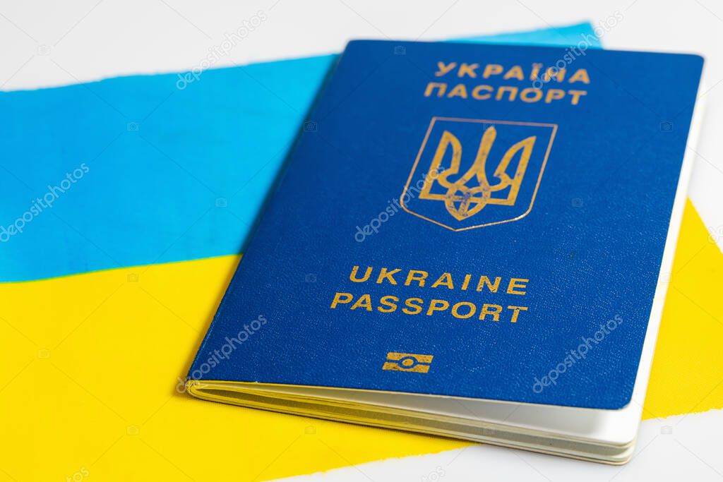 Ukrainian biometric passport on background of Ukrainian flag.  Document for traveling abroad, concept. Isolated on a white background