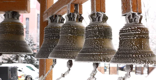 Ortodoks Kilisesi 'nin arka planında gümüş çanlar olan karla kaplı küçük bir çan kulesi. Çanlar, çıngıraklı yılanlar, kış, Noel. Ortodoksluk kavramı.