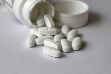 Beyaz, dikdörtgen haplar beyaz arka planda bir şişeden dökülmüş. Kopyalama alanı ile, sığ alan derinliği. Tıp konsepti