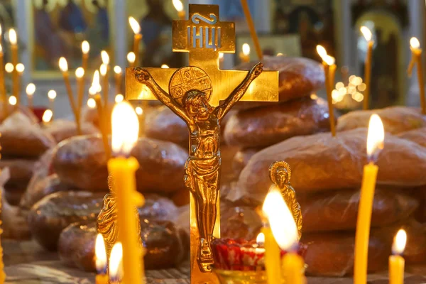 Funeral service, funeral liturgy in the Orthodox Church. Christians light candles in front of the Orthodox cross with the crucifix, the concept of Orthodox faith and religion.
