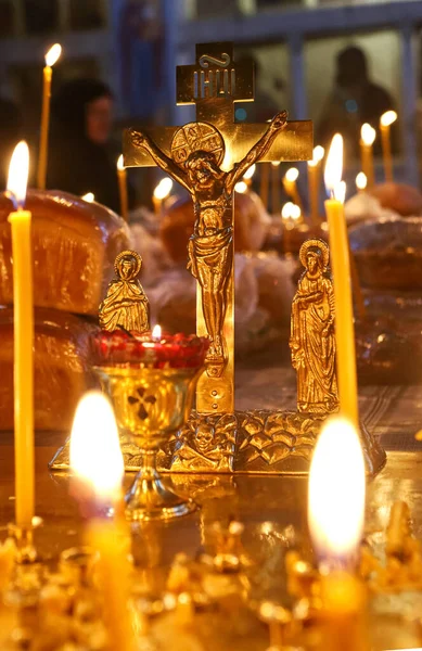 Funeral service, funeral liturgy in the Orthodox Church. Christians light candles in front of the Orthodox cross with the crucifix, the concept of Orthodox faith and religion.