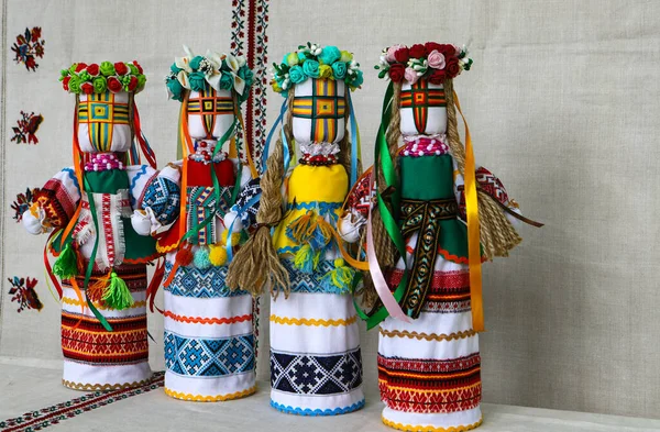 Geleneksel Ukrayna halk oyuncakları motanka, halk kostümlü el yapımı oyuncak bebek, ev yapımı işlemeli tuvalin arka planında. Ukrayna kültürü, halk sanatları.