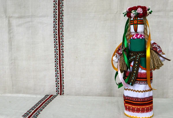 Traditional Ukrainian folk dolls motanka, handmade doll in folk costume, against the background of home-woven embroidered canvas. Culture of Ukraine, folk crafts