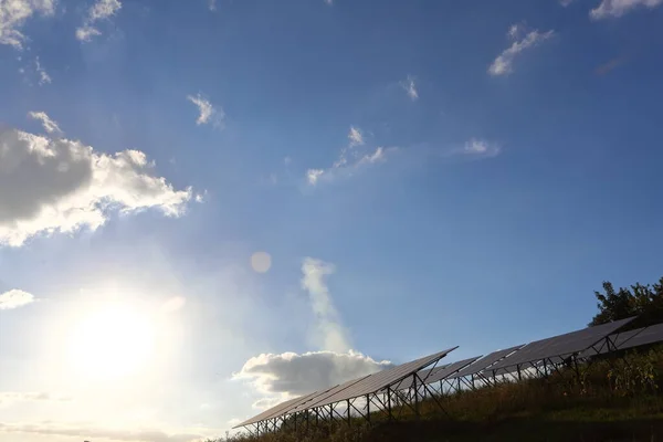 Photoelectric batteries at sunset. Sun glare, blue saturated sky, white clouds. Solar panels. The concept of alternative energy