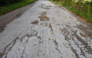 Eski hasarlı, terk edilmiş, tahrip edilmiş, çukurlu, tehlikeli asfalt yolu..