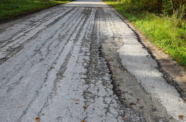 Eski hasarlı, terk edilmiş, tahrip edilmiş, çukurlu, tehlikeli asfalt yolu..