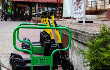 Şehir sokaklarında modern elektrikli scooterların park yeri. Modern siyah ve sarı elektrikli scooterlar modern bir şehrin caddesinde park edilmiş.