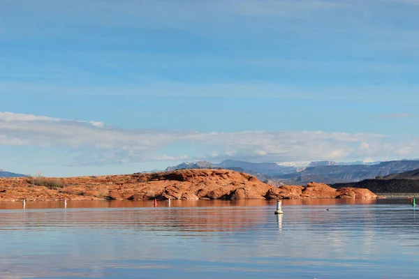Utah 'taki Sand Hollow Eyalet Parkı' nın kırmızı kıyı şeridine uzanan gölün sakin suları..