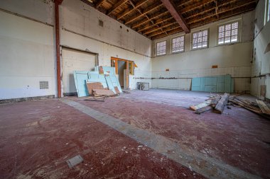 Yıkıma uğrayan eski bir binanın içinde. Ekipman ve enkaz, moloz ve atık görünür.