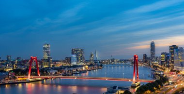 Gece Rotterdam 'ın gökyüzü çizgisi Maas nehri üzerinde Willems köprüsünü ve Erasmus köprüsünü gösteriyor.
