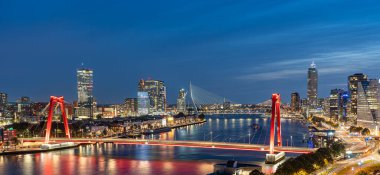 Gece Rotterdam 'ın gökyüzü çizgisi Maas nehri üzerinde Willems köprüsünü ve Erasmus köprüsünü gösteriyor.