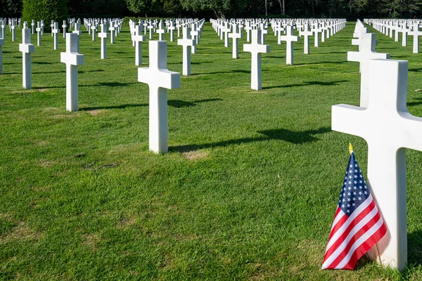 An American flag stands at the gravestone of a killed soldier at the American war cemetery in Normandy, France