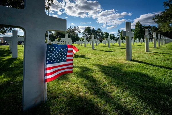 An American flag stands at the gravestone of a killed soldier at the American war cemetery in Normandy, France