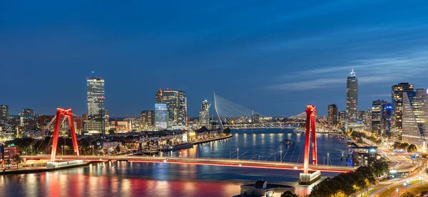Gece Rotterdam 'ın gökyüzü çizgisi Maas nehri üzerinde Willems köprüsünü ve Erasmus köprüsünü gösteriyor.