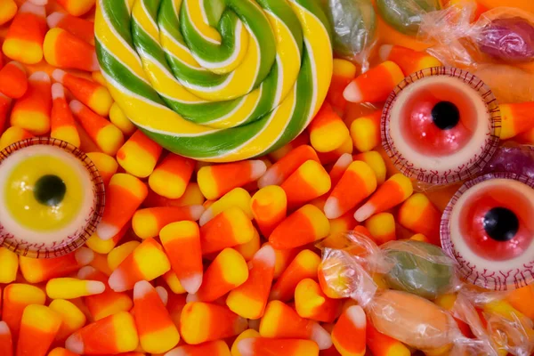 Halloween candy background close-up top view stock images. Halloween sweet candy corn, lollipop, scary eyes stock photo. Different types of candies images