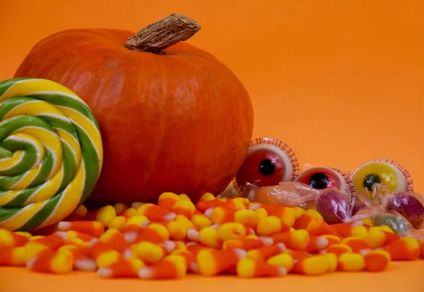 Halloween candy still life on orange background stock images. Halloween sweet candy corn, pumpkin, lollipop, scary eyes stock photo. Different types of candies images