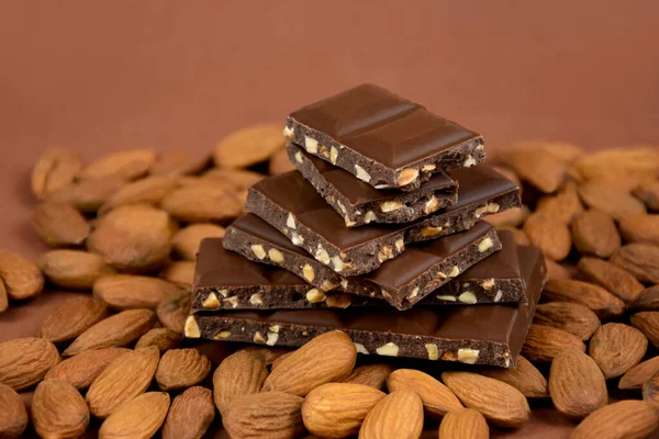 アーモンドストック画像付きヒープ上のミルクチョコレートキューブ 茶色の背景にアーモンドチョコレートの作品ストック画像 — ストック写真