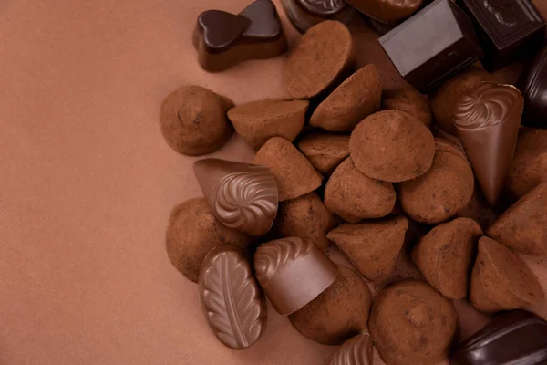 チョコレートのプラリネとトリュフの茶色の背景トップビューのストック画像 チョコレートはテキストのためのコピースペースが付いている茶色の背景の説教 様々なチョコレートキャンディーのフレームの写真 — ストック写真