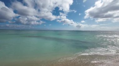 Meşhur Waikiki sahilinin sarı kumlarında yürüyorum. Pasifik Okyanusu 'nun sıcak dalgaları tropik bir Waikiki plajını kaplıyor. Turkuaz su