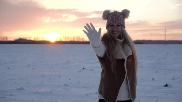 Молодая блондинка зимой на закате с красным небом смеется и смущается — стоковое видео