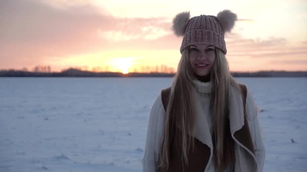 Blondýny dívka ve sněhu zimní pole při západu slunce úsměv a ukazuje palec nahoru gesto jako — Stock video