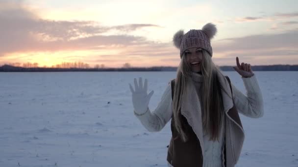 Dziewczyna w zimowym polu o zachodzie słońca sprawia, że połykanie wygłupiając się wokół uśmiech daje i tańczy — Wideo stockowe