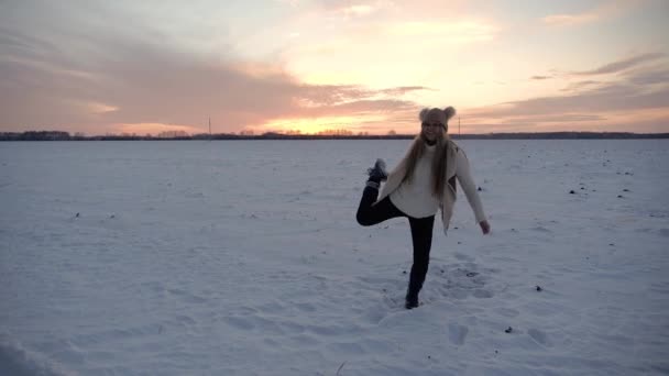 Flicka på vintern fält vid solnedgången gör svälja lura runt leende ge och dansa — Stockvideo