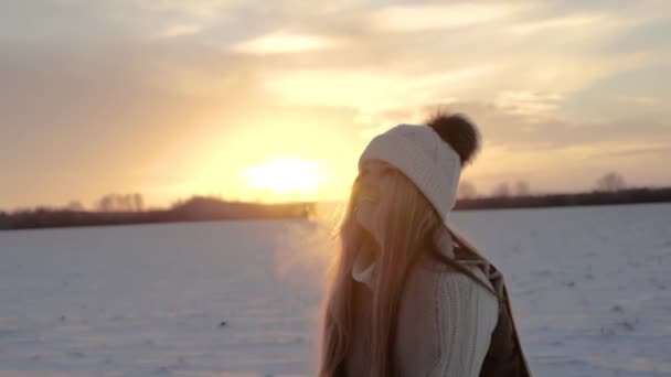 Chica en invierno al atardecer lanza nieve al aire. Movimiento lento en la hora dorada — Vídeos de Stock