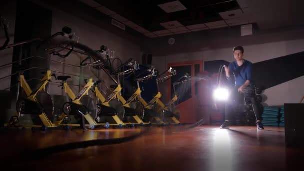Молодой парень делает упражнение с веревкой в тренажерном зале с красивой, контур света 4K — стоковое видео