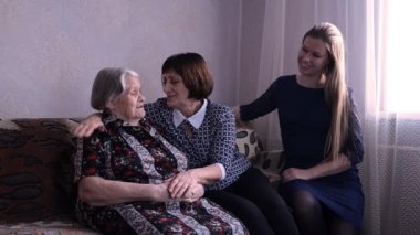Çok yaşlı büyükanne torun aile toplantısında. Yetişkinler yaşlıları ziyaret eder.