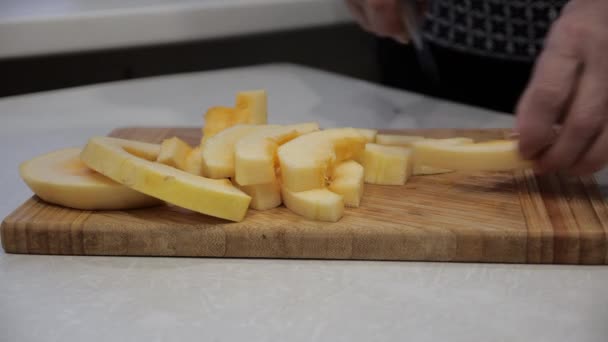Krojenie cukinii na drewnianej desce na białym stole z dużym nożem kucharskim. — Wideo stockowe