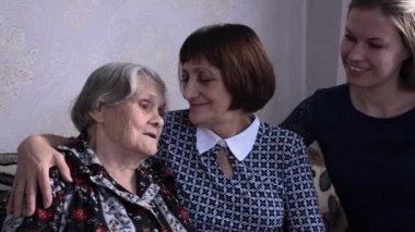 Çok yaşlı büyükanne torun aile toplantısında. Yetişkinler yaşlıları ziyaret eder.