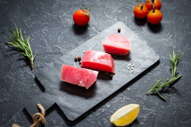 Çiğ ton balığı filetosu. Siyah taşlı arka planda deniz ürünleri.