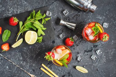 Yaz tazeleyici mojito kokteyli, çilekli, naneli ve limonlu. Koyu taştan bir masada içkileri çırpmak için. Üst görünüm