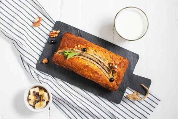 Banana bread or cake on white wooden table. Delicious homemade dessert, tasty snack or morning breakfast. Top view