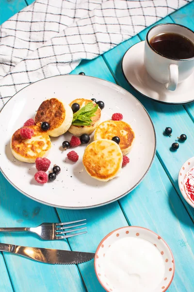 Cottage cheese pancakes, ricotta fritters or syrniki with currant and raspberry. Healthy and delicious morning breakfast.