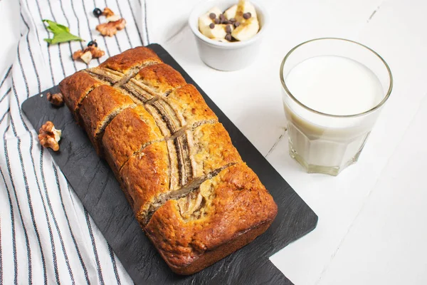 Banana bread or cake on white wooden table. Delicious homemade dessert, tasty snack or morning breakfast.