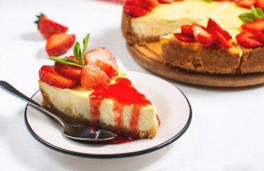 Piece of cheesecake with fresh strawberries jam and mint. Tasty homemade cheesecake on a white background.