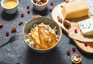 Armut ve Gorgonzola yulaf ezmesi ve siyah taş masada ceviz..