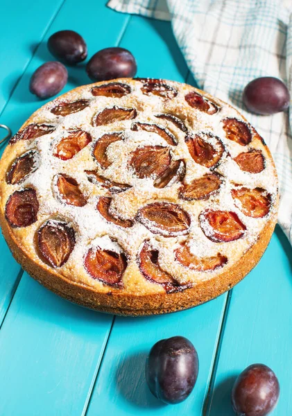 Homemade delicious plum tart with with sugar powder on blue wooden table