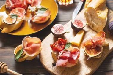 Geleneksel İspanyol tapas setiyle aperatifler. İtalyan usulü jambonlu, krem peynirli ve incirli bruschetta..