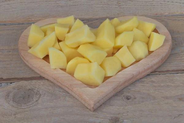 Yemek yaparken kalp şeklinde bir tabakta dilimlenmiş patatesler. — Stok fotoğraf