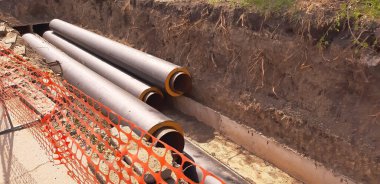 Hendeğin yanındaki merkezi ısıtma boruları kurulum için hazır..