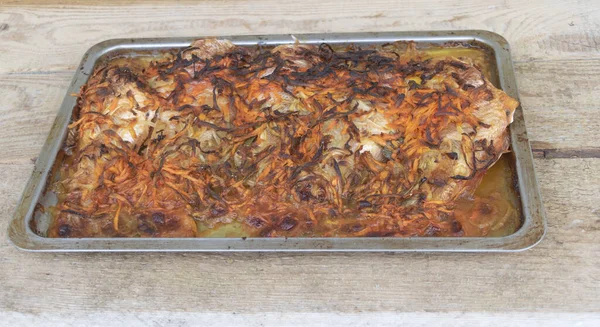 Pescado al horno en un rollo con una capa de zanahorias y cebollas doradas — Foto de Stock