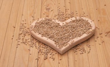 Kalp şeklinde bir tahta tabakta buğday taneleri. Yaklaş..